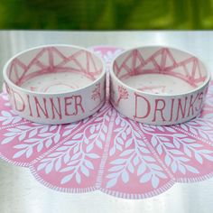 two pink and white bracelets sitting on top of a table next to each other