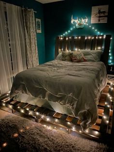 a bed with lights on the headboard and foot board in front of it is lit up by string lights