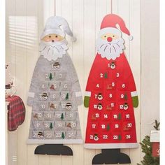 two christmas calendars hanging on the wall next to a christmas tree and stockings with santa claus