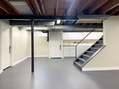 an empty room with stairs leading up to the kitchen