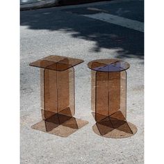 two glass side tables sitting on the sidewalk