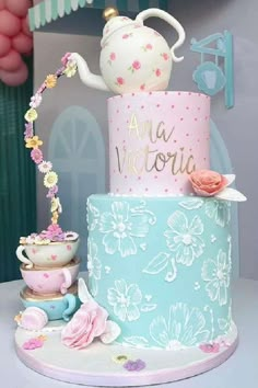 a three tiered cake decorated with flowers and teapots