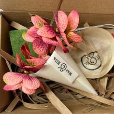 pink flowers are sitting in a cardboard box