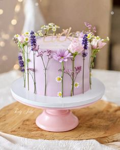 a pink cake decorated with flowers on top of a table