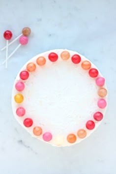 a white plate topped with candy covered cake next to two lollipop sticks