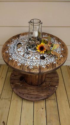 a wooden table topped with a vase filled with sunflowers and rocks sitting on top of a wooden floor