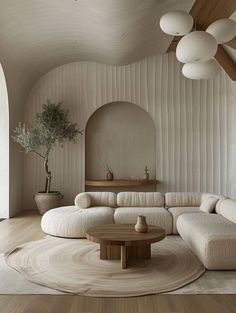 a living room with white couches and round tables in the center, surrounded by wooden flooring