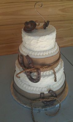 a three tiered wedding cake with horseshoes and rope