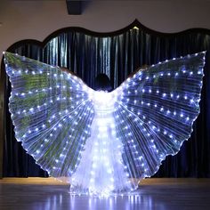 a woman is standing in front of a curtain with lights on it and her wings spread out