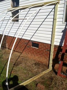 an outdoor garden with some plants growing out of it's sides and the side of a house in the background