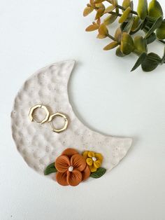 a ceramic moon with flowers on it and two gold rings sitting on top of it