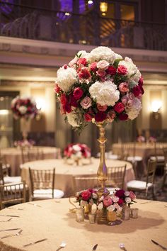 a tall vase filled with red and white flowers on top of a table covered in gold