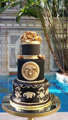 a three tiered cake sitting on top of a metal stand next to a swimming pool