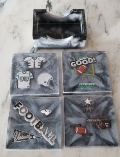 four magnets with different sports logos on them sitting on a marble counter top next to a plastic bag