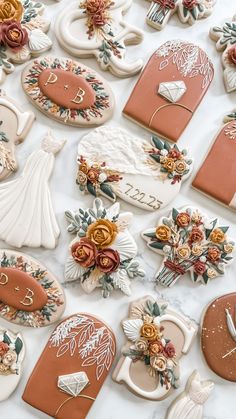 many decorated cookies on a table with flowers and other decorations around them, including wedding rings