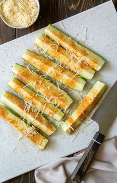 sliced zucchini on a cutting board with cheese and parmesan sprinkles