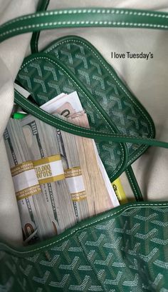 a green purse filled with money sitting on top of a bed