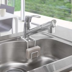 a stainless steel sink with an overflowing faucet in front of a window