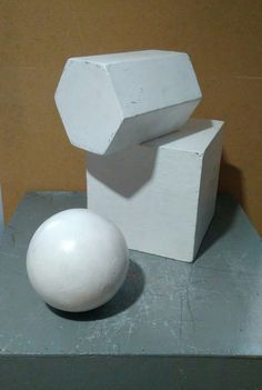 a white object sitting on top of a cement block next to a small round ball