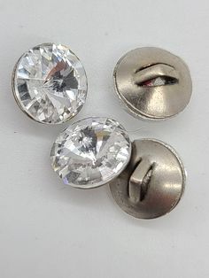 three silver colored buttons with clear crystal stones