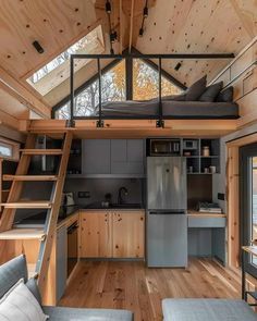 the interior of a tiny cabin with wood floors and stairs leading up to the loft