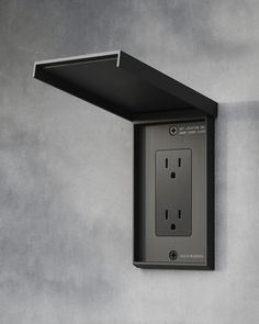 an electrical outlet attached to the side of a wall with a black cover over it