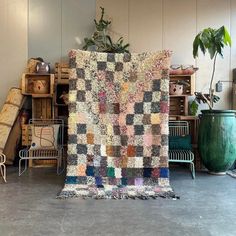 a large patchwork quilt sitting on top of a floor next to a potted plant