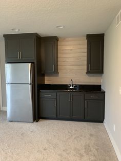 an empty kitchen with gray cabinets and silver appliances