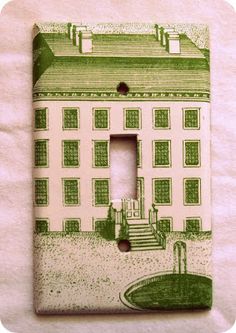 a green and white light switch cover with a drawing of a house on the front