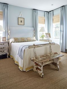 a bed room with a neatly made bed and a bench in front of the window