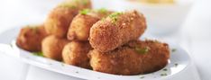 some fried food on a white plate with parsley sprinkled around it's edges