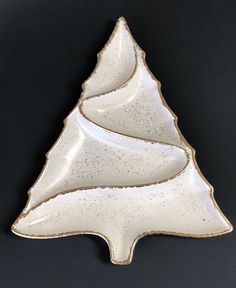 a white ceramic christmas tree dish on a black background