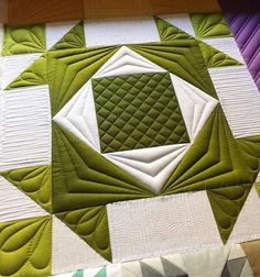 a green and white quilted table topper with a square in the center on it