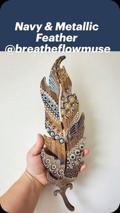 a hand holding a decorative bird made out of wood