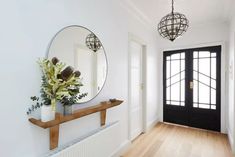 an entryway with a mirror, vase and plant on the shelf next to it