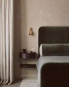 a bed sitting next to a window in a room with curtains on the windowsill