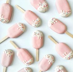 there are many pink and white pops with sprinkles on them in the shape of nails