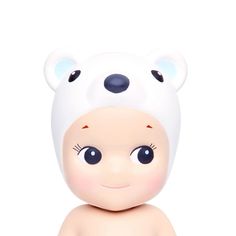 a small toy bear with big eyes and a hat on it's head, sitting in front of a white background