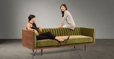 two women are sitting on a green couch