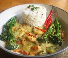 a bowl with rice, broccoli and red peppers in it on a table