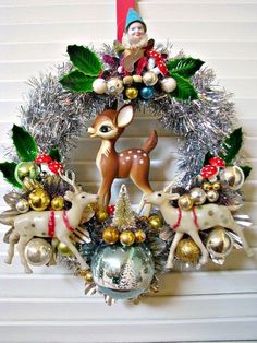 a christmas wreath hanging on the wall with ornaments around it and a deer figurine