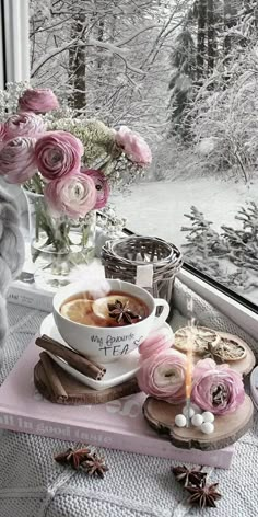 a cup of hot chocolate on a tray next to a window sill with pink flowers