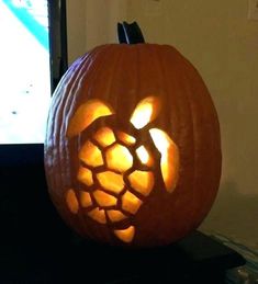 a carved pumpkin with an image of a turtle on it's face in front of a tv