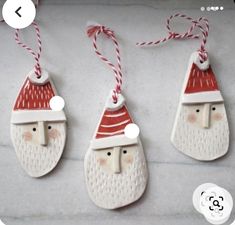 three ceramic santa claus ornaments hanging from strings