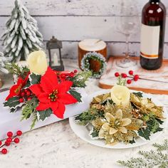 two white plates topped with poinsettia and greenery next to bottles of wine