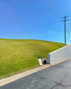 an empty parking lot next to a green hill