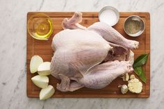 a whole chicken on a cutting board with ingredients