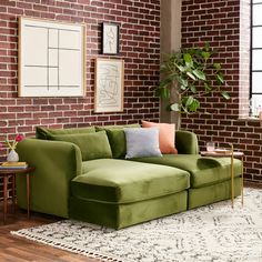 a green couch sitting on top of a wooden floor next to a white and black rug