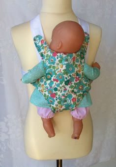 a baby doll that is laying down on a mannequin's torso, wearing a dress