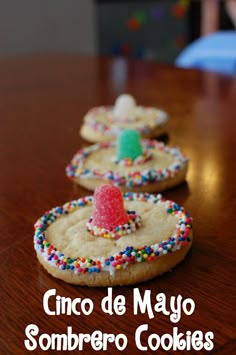 three decorated cookies sitting on top of a wooden table